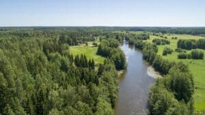 Kymijoen jokimaisemat ilmasta kuvattuna. Joki virtaa hiljalleen villa Strukan, Villa Kaunisvirran ja Kivikosken mökin editse. Pyhtää