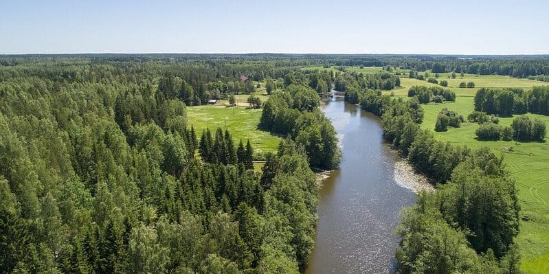 Jokimaisema Pyhtää Kymijoen jokimaisemat ilmasta kuvattuna. Joki virtaa hiljalleen villa Strukan, Villa Kaunisvirran ja Kivikosken mökin editse. Pyhtää