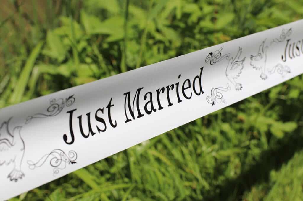 Vihreän nurmikon ja luonnon keskellä oleva "Just Married" -kyltti, sopii häätarjoiluihin ja juhlatilaisuuksiin.