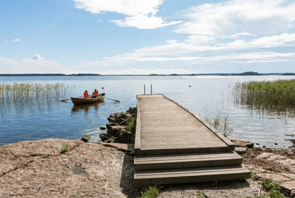 Laituri ja soutuvene käytettävissä skitunäsin merenrantamökillä.